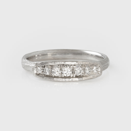 Platinum ring with diamonds on a light gray background