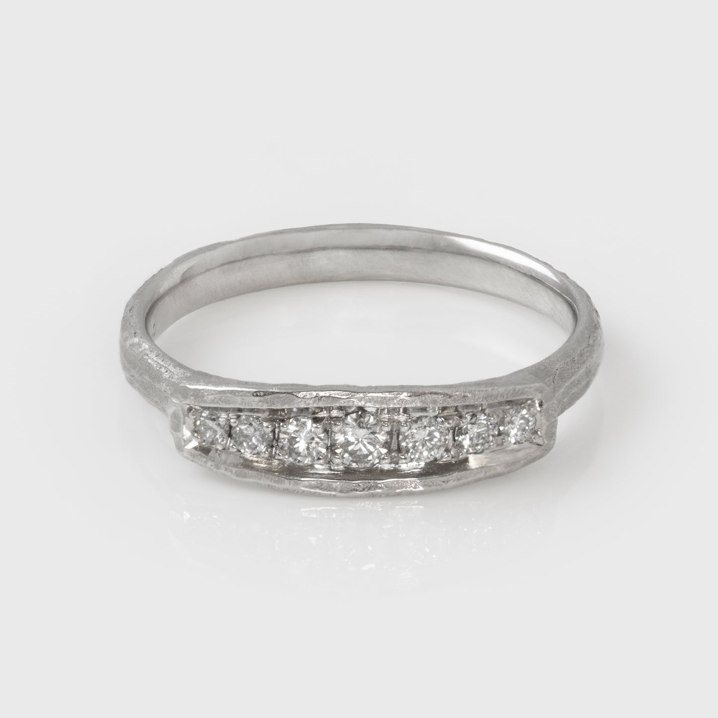 Platinum ring with diamonds on a light gray background, view from above