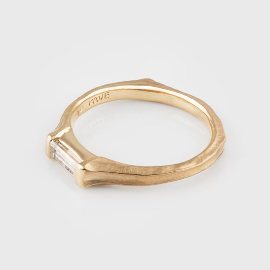 Gold ring with a diamond on a light gray background