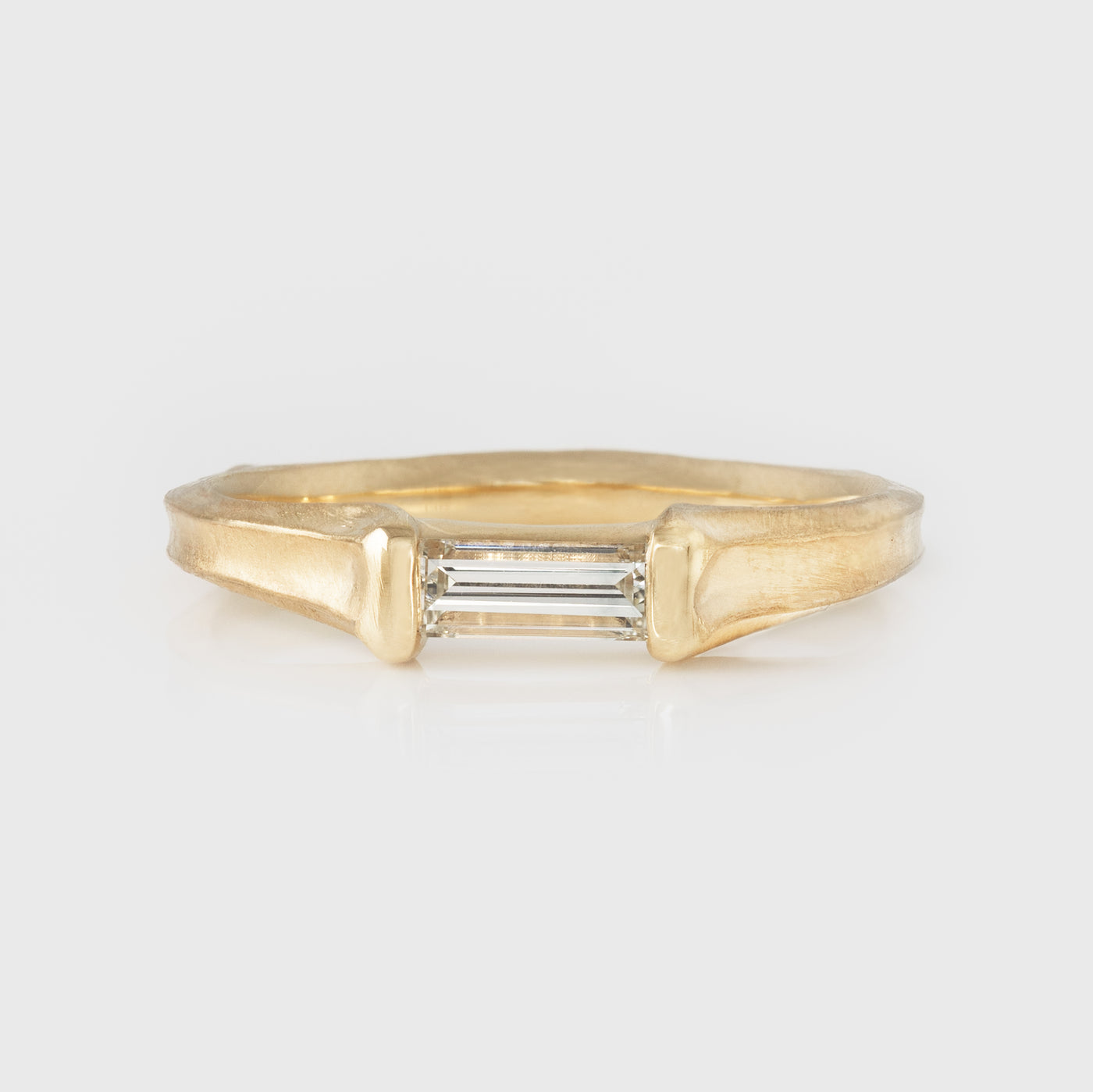 Gold ring with a diamond on a light gray background