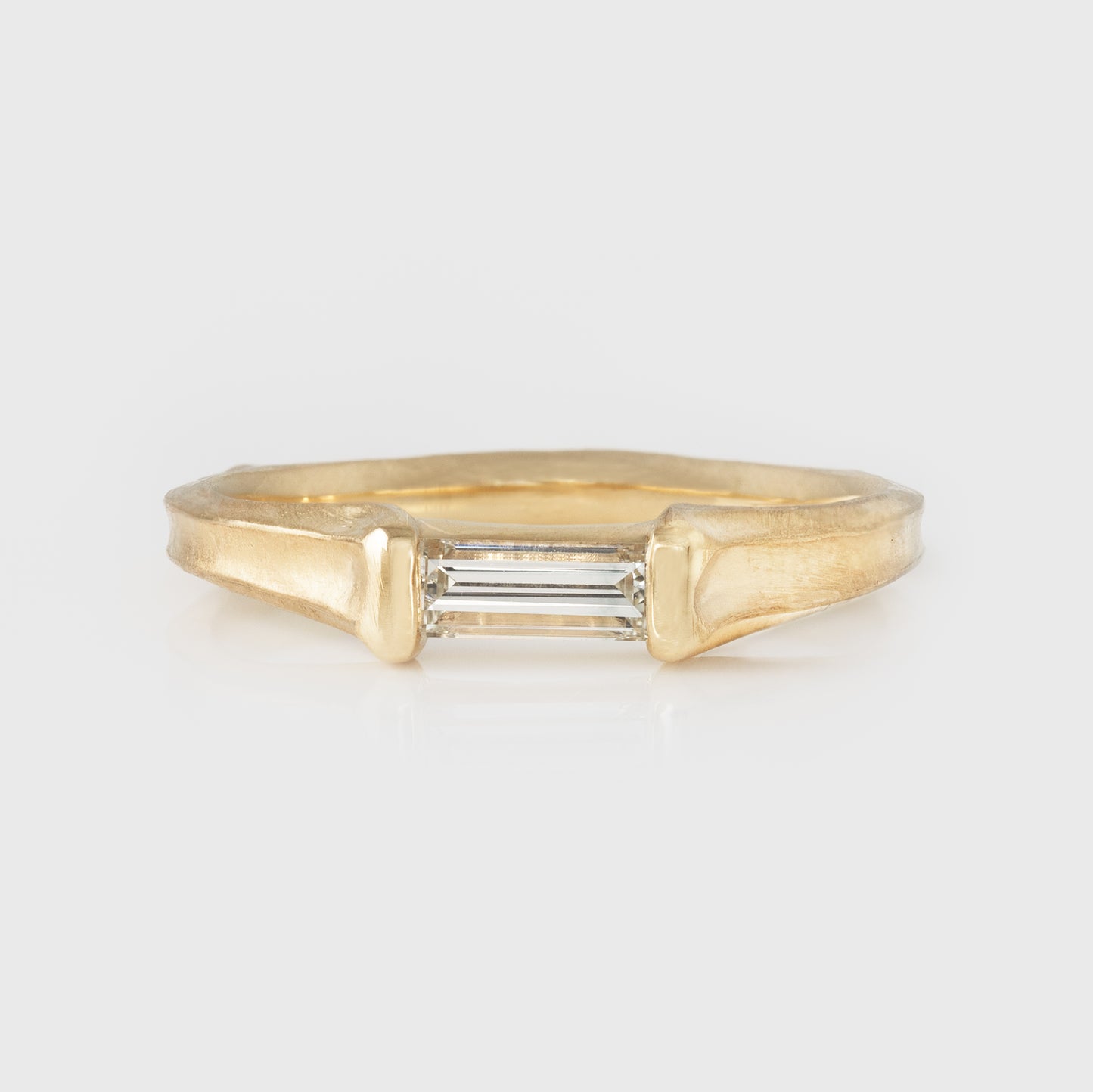 Gold ring with a diamond on a light gray background