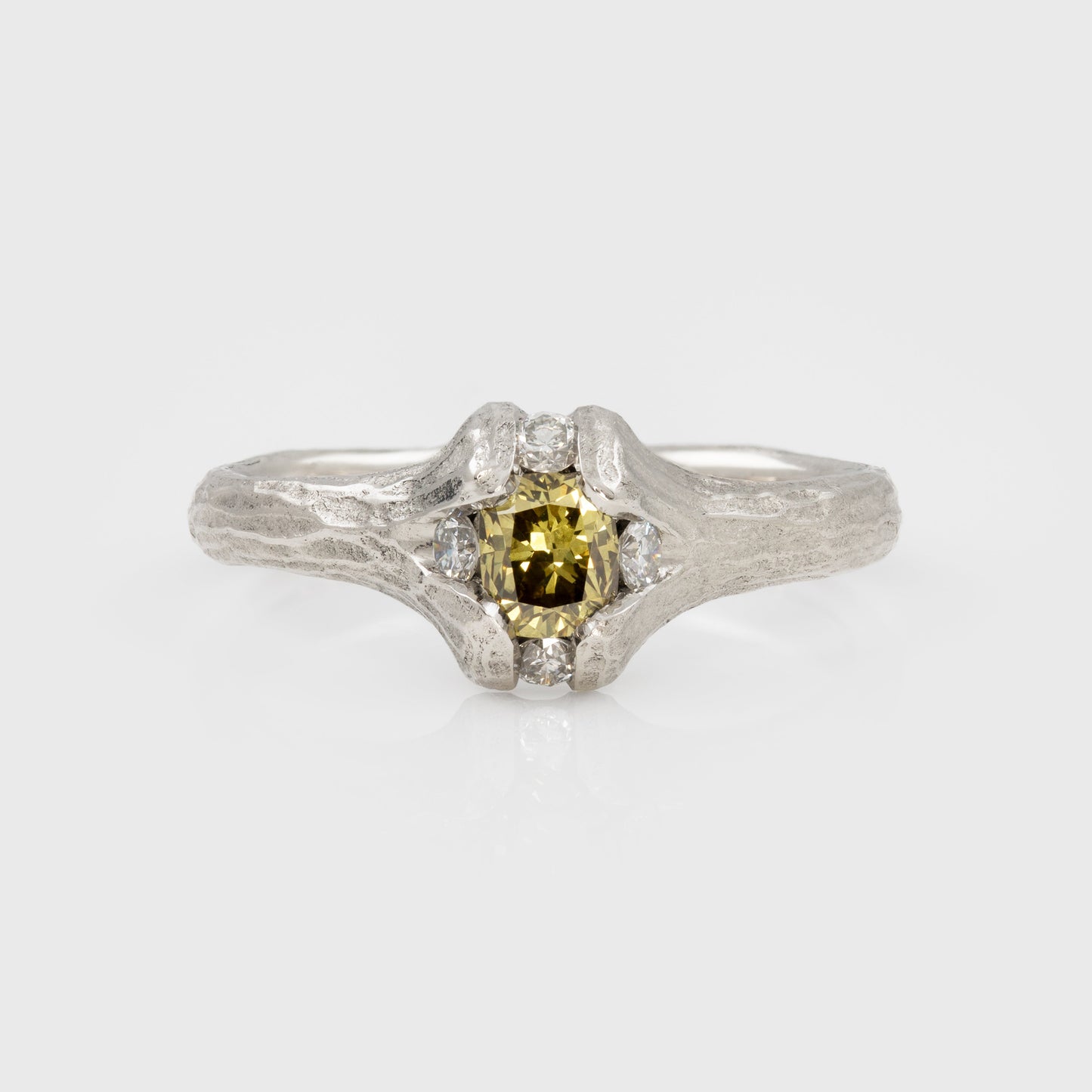 Platinum ring with yellow-brown diamond and redwood bark texture on a white background