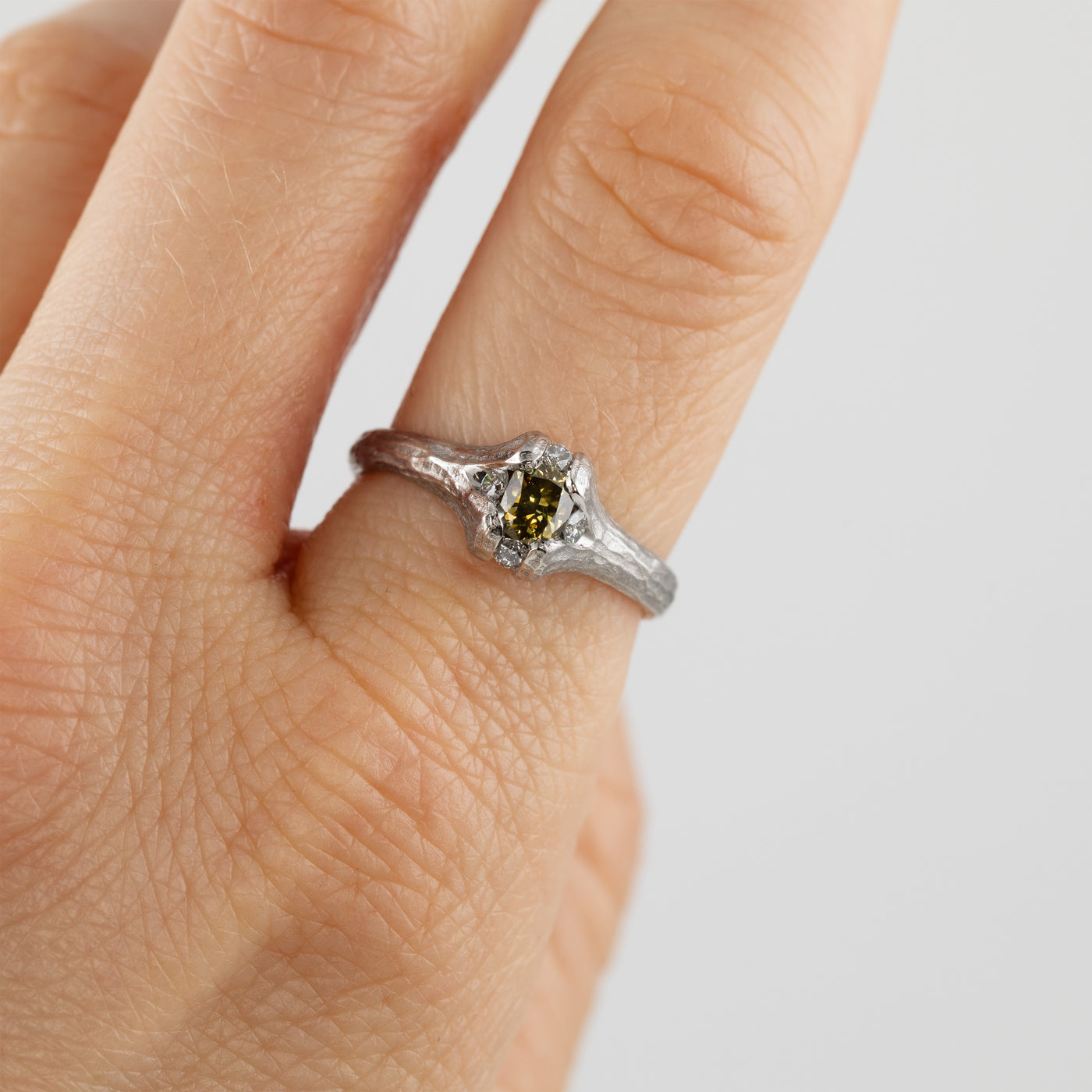 Platinum ring with yellow-brown diamond and redwood bark texture on a hand
