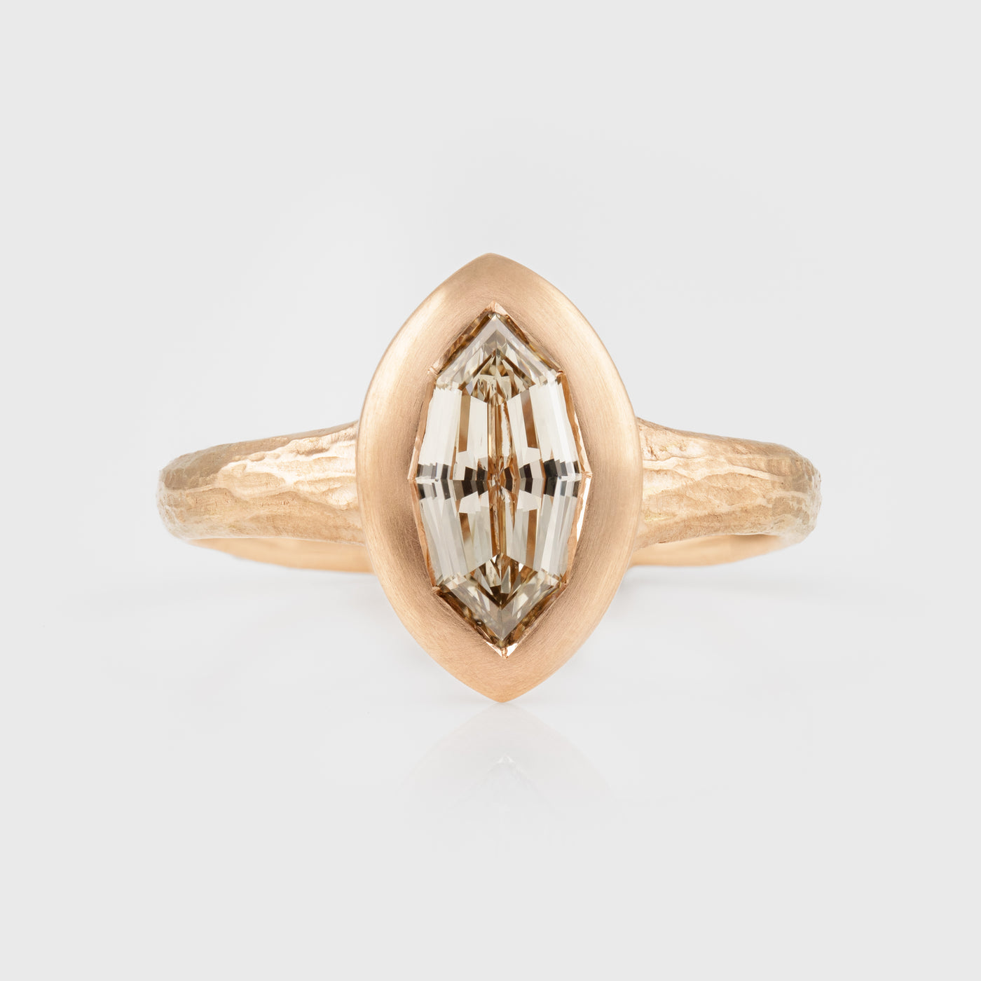 Rose gold ring with a marquise-shaped diamond on a light gray background