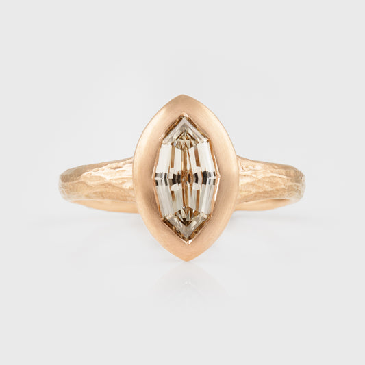 Rose gold ring with a marquise-shaped diamond on a light gray background