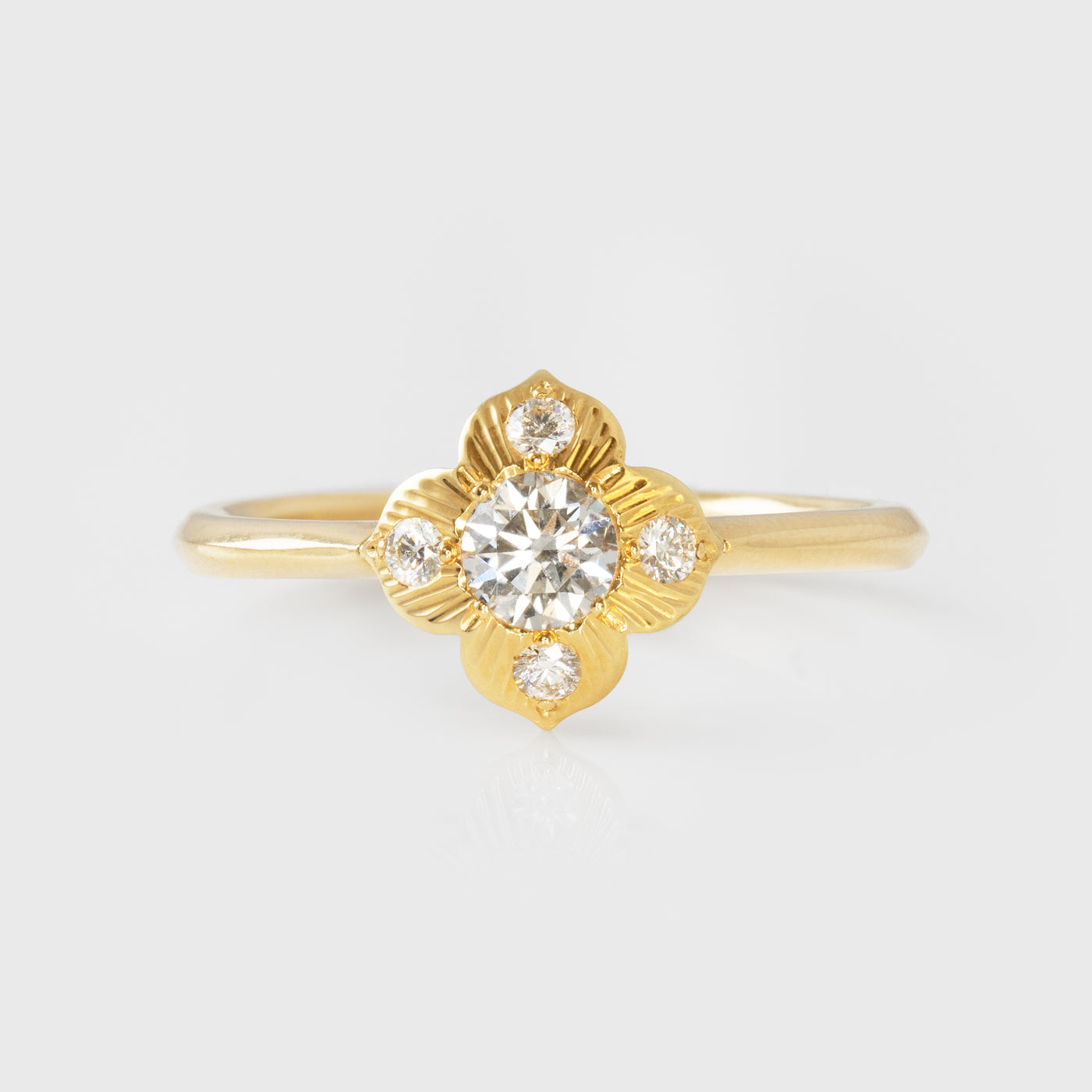 Gold ring with a diamond  in a flower shapeon a light gray background
