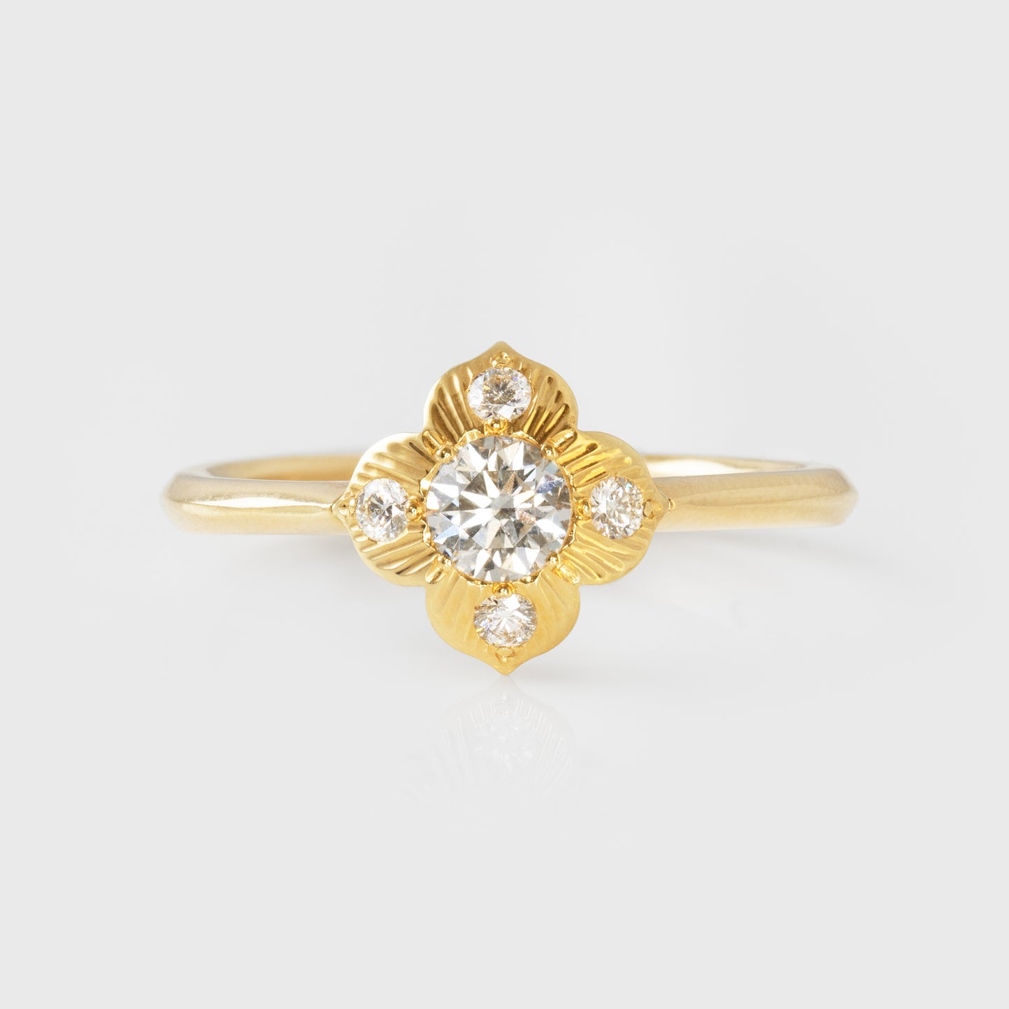 Gold ring with a diamond  in a flower shapeon a light gray background