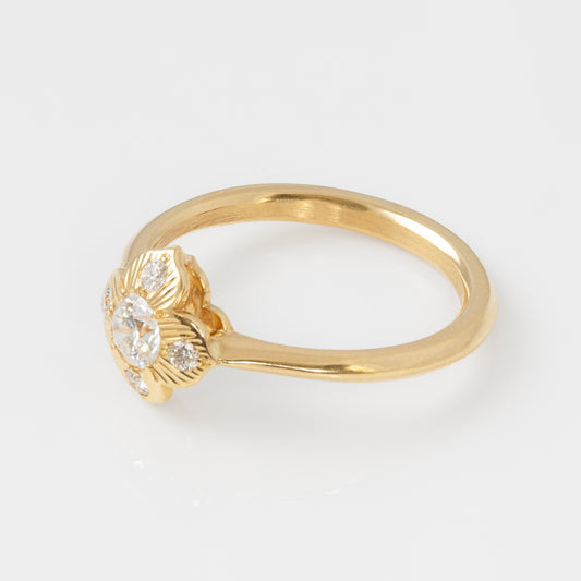 Gold ring with a diamond  in a flower shapeon a light gray background