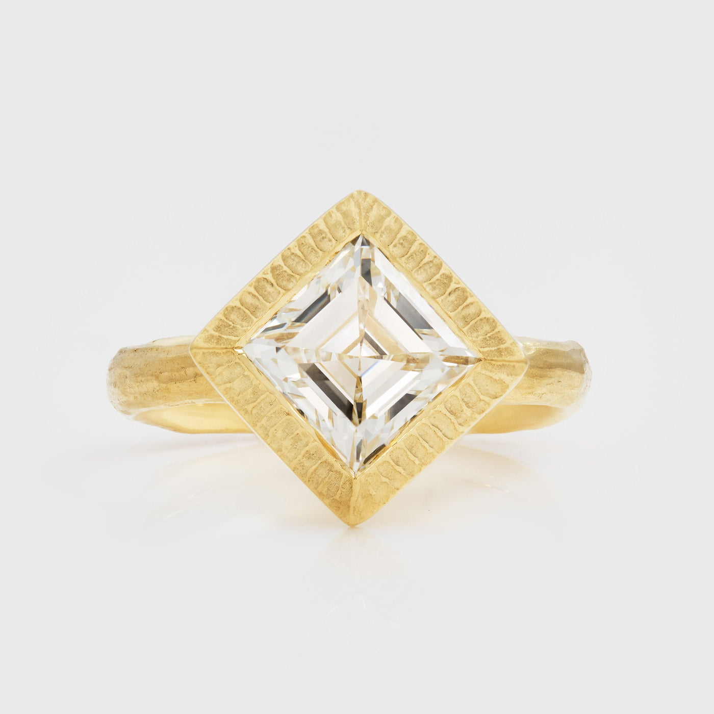Gold ring with a square-cut diamond on a light gray background