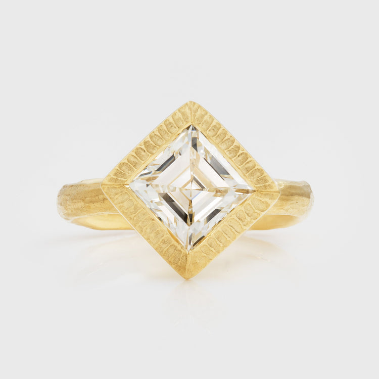 Gold ring with a square-cut diamond on a light gray background