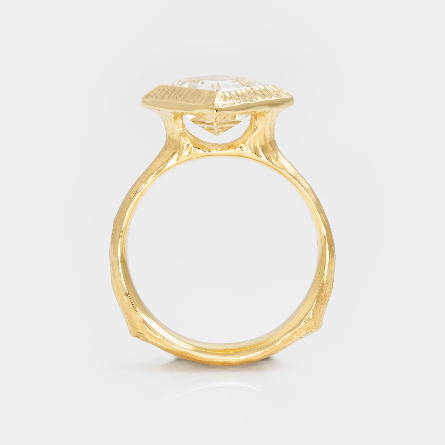 Gold ring with a diamond on a light gray background side view