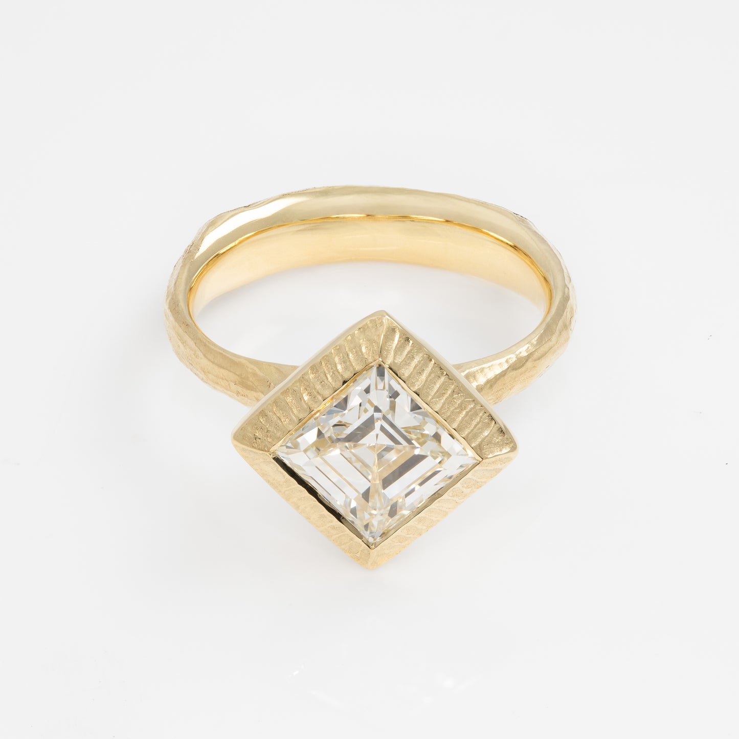 Gold ring with a square-cut diamond on a white background