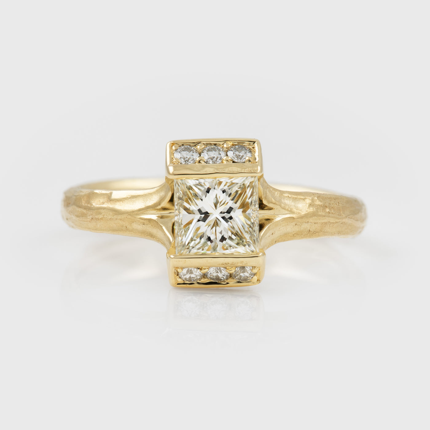 Gold ring with a large diamond and smaller diamonds on a light gray background