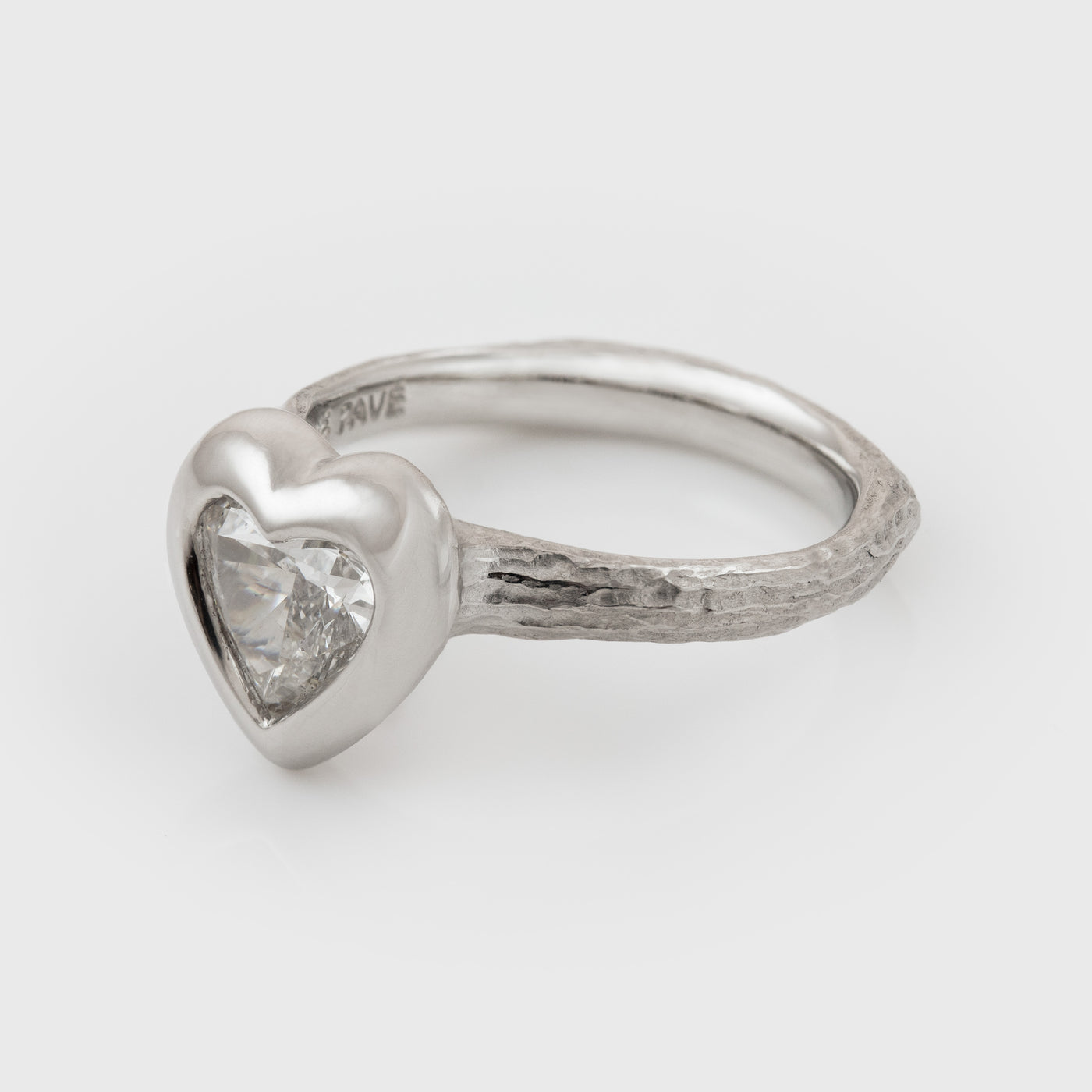 Platinum heart shaped diamond ring on a white background, side angle