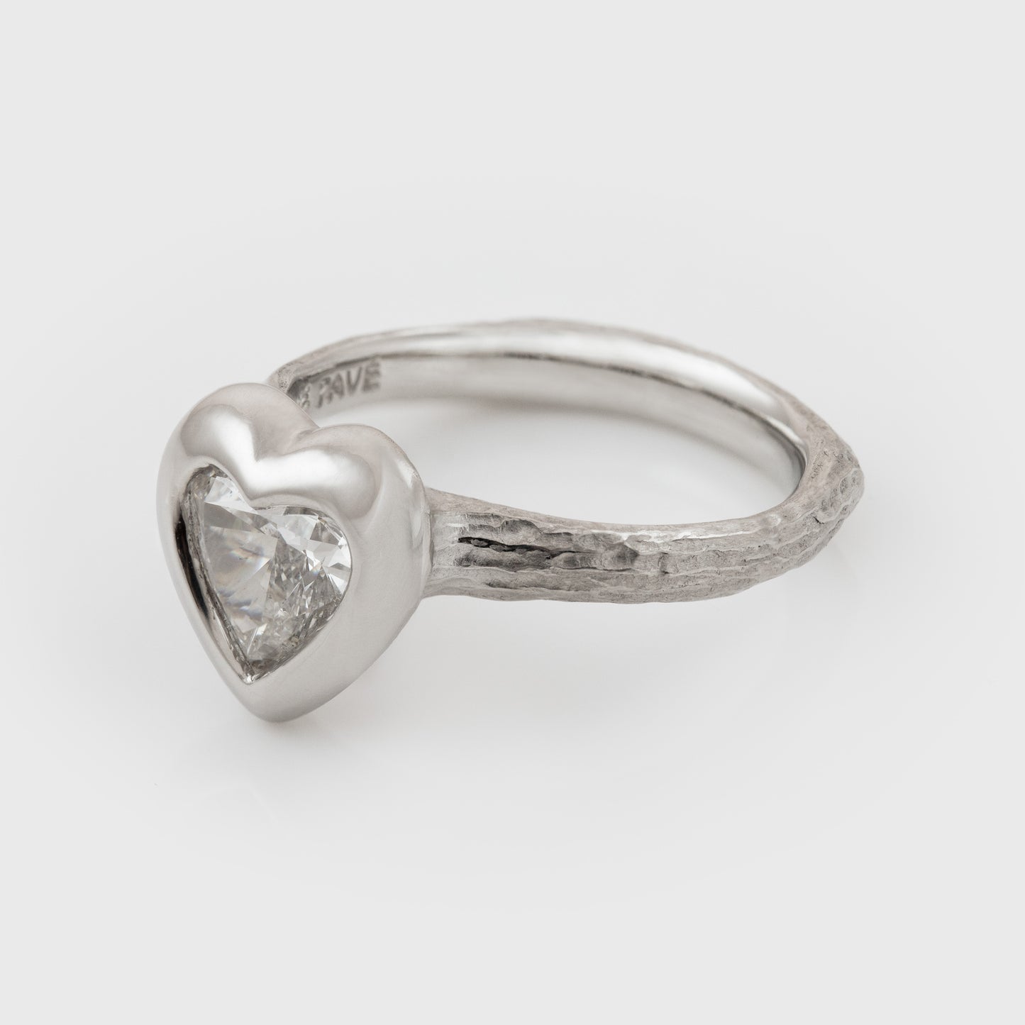 Platinum heart shaped diamond ring on a white background, side angle