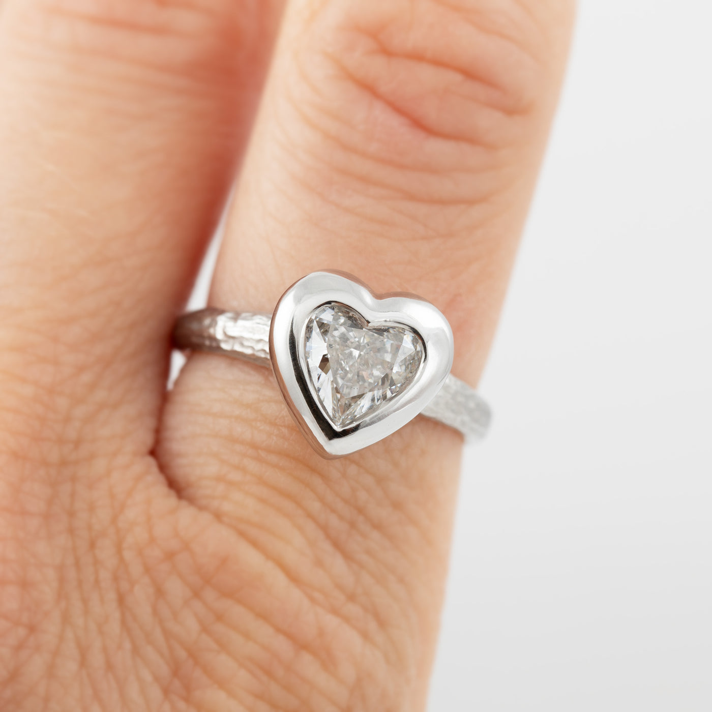 Platinum heart shaped diamond ring on a index finger