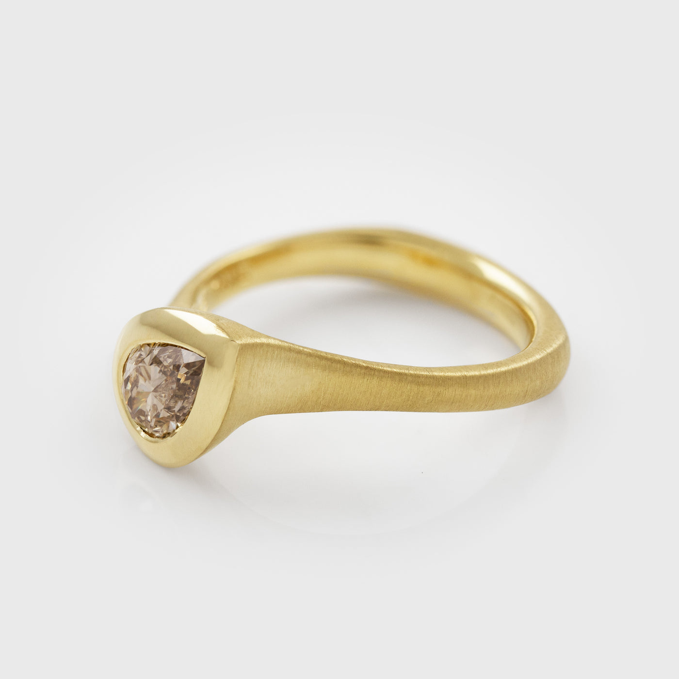 Side view of yellow gold ring featuring bezel set pear brilliant champagne Diamond