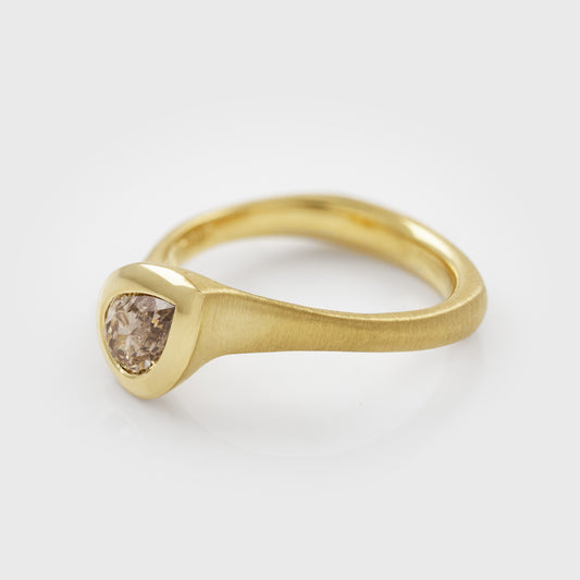 Side view of yellow gold ring featuring bezel set pear brilliant champagne Diamond