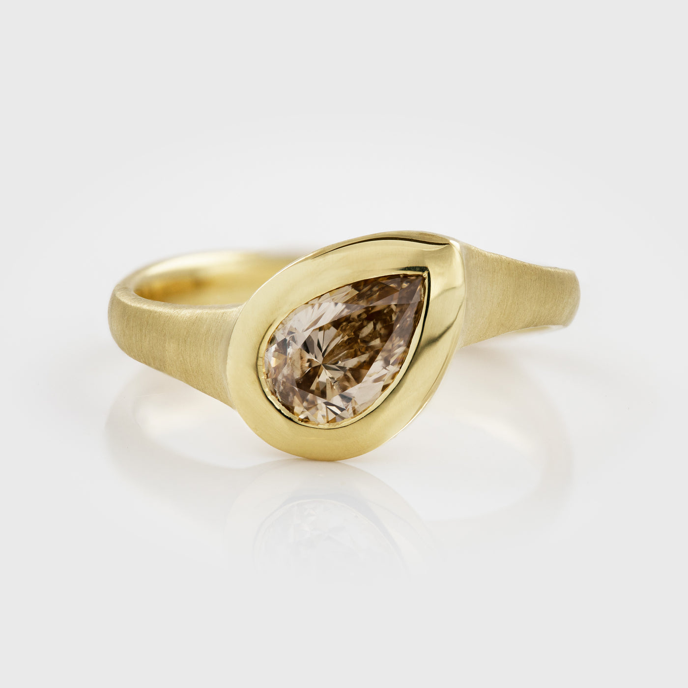 Yellow gold ring featuring bezel set pear brilliant champagne Diamond