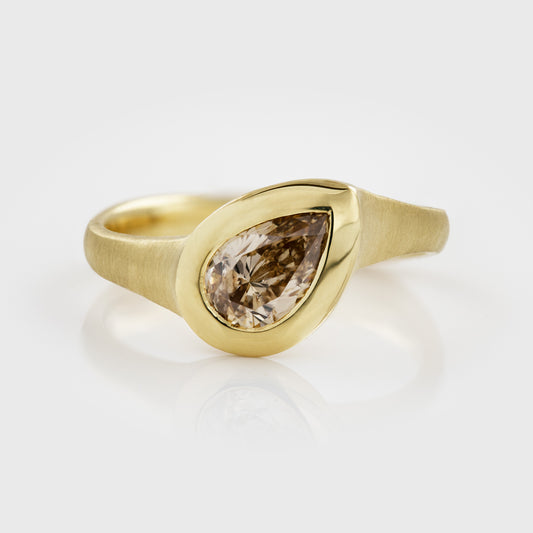 Yellow gold ring featuring bezel set pear brilliant champagne Diamond