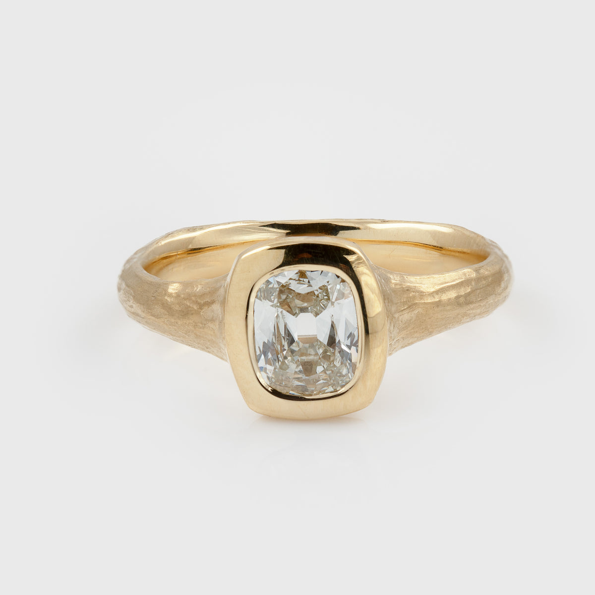 Yellow gold ring featuring a hybrid old-cut diamond center stone set in a high-polish bezel with a textured band, photographed on a white background.