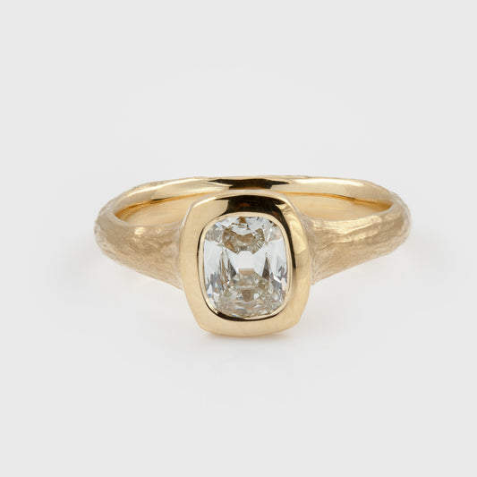 Yellow gold ring featuring a hybrid old-cut diamond center stone set in a high-polish bezel with a textured band, photographed on a white background.