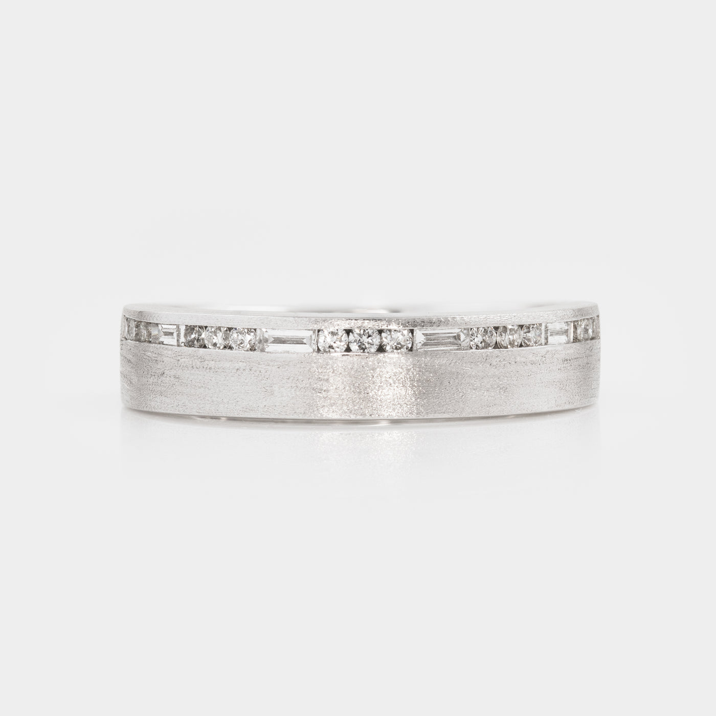 Silver ring with embedded diamonds on a light gray background