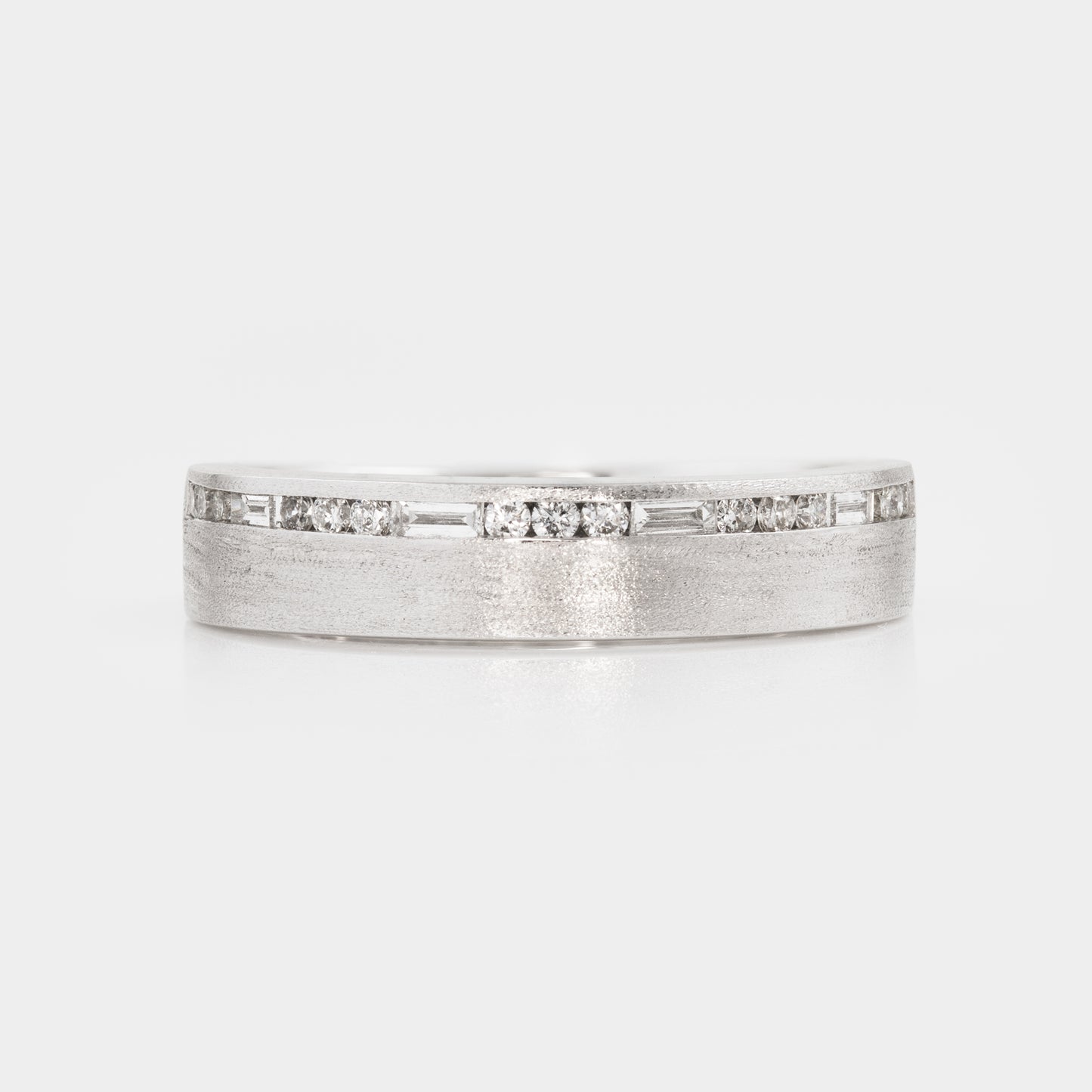 Silver ring with embedded diamonds on a light gray background