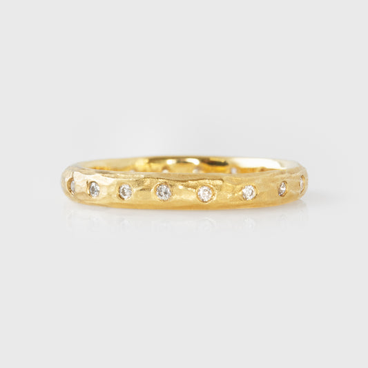 Gold ring with flush set diamonds on a light gray background