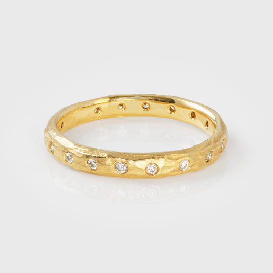 Gold ring with flush set diamonds on a light gray background