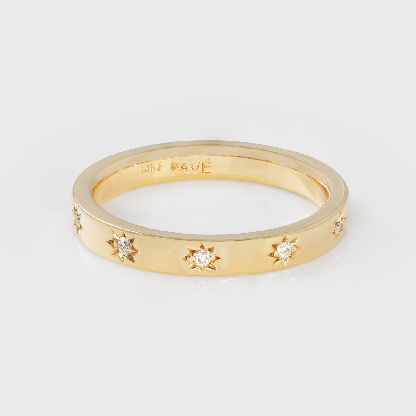 Gold ring with diamonds in star-shaped settings on a light gray background