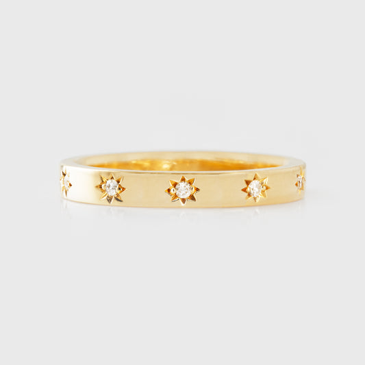 Gold ring with diamonds in star-shaped settings on a light gray background