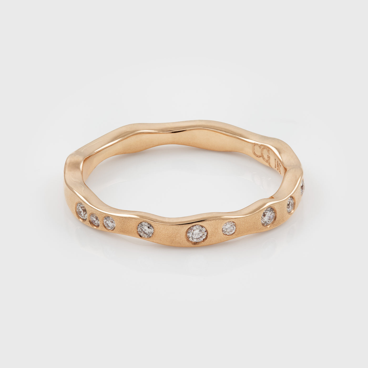 Rose gold ring with diamonds on a light gray background
