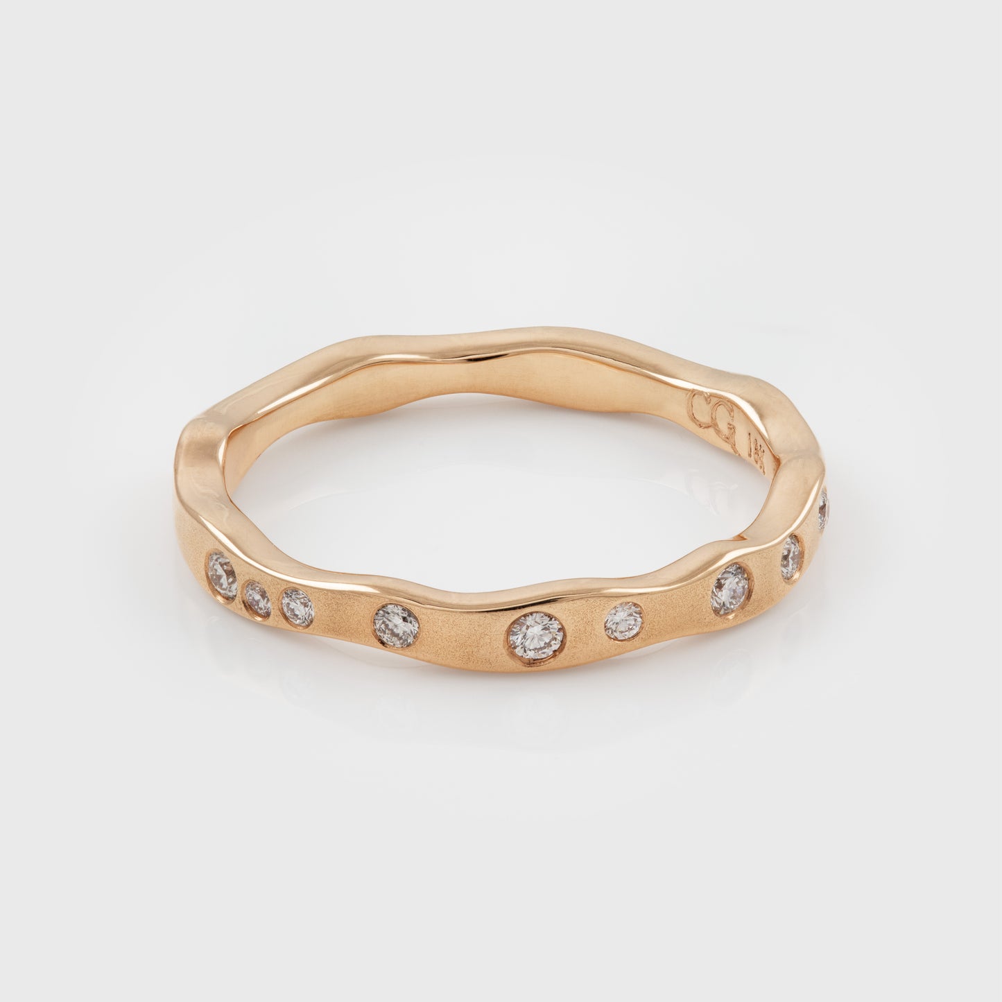 Rose gold ring with diamonds on a light gray background