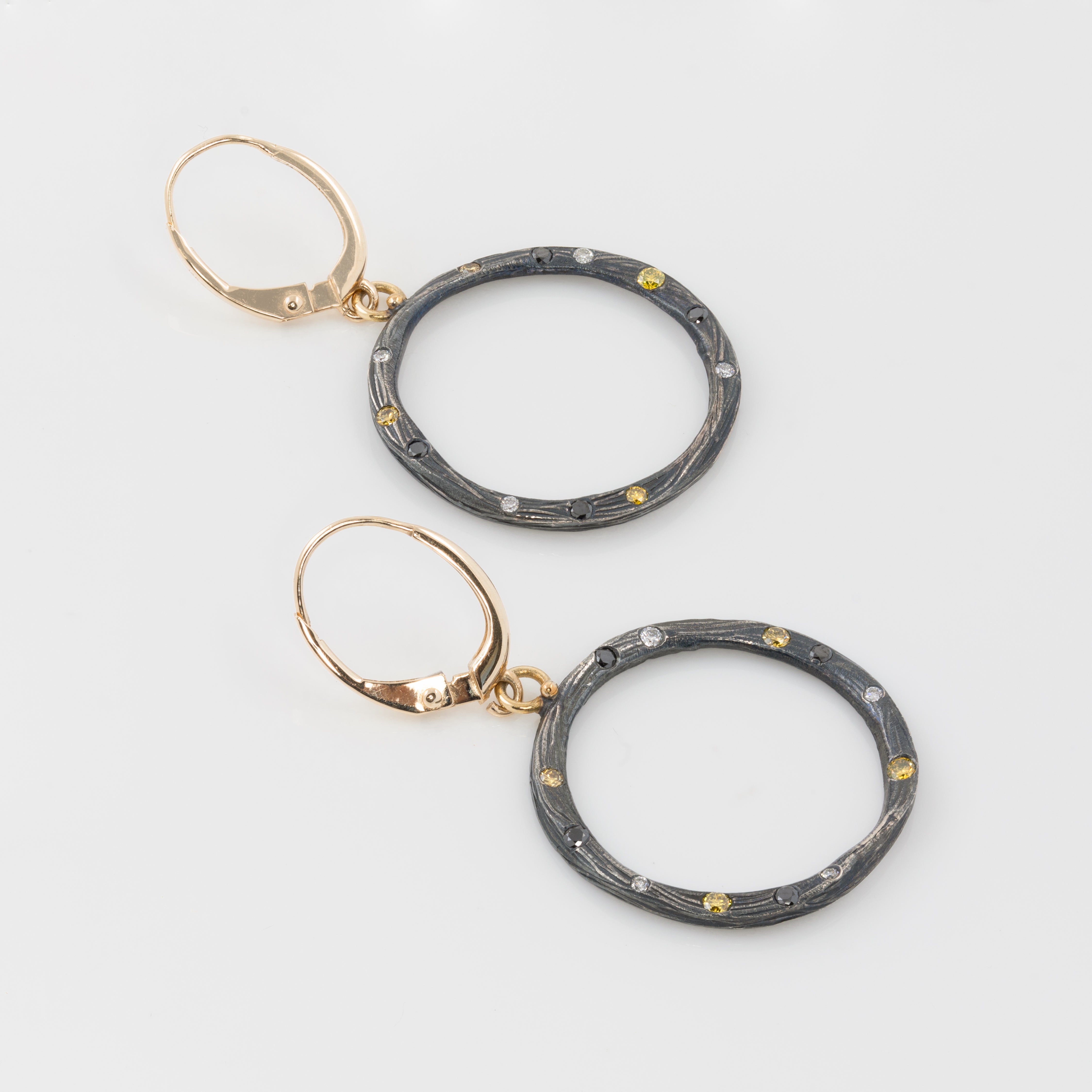 Pair of hoop earrings with gold and black design on a light gray background