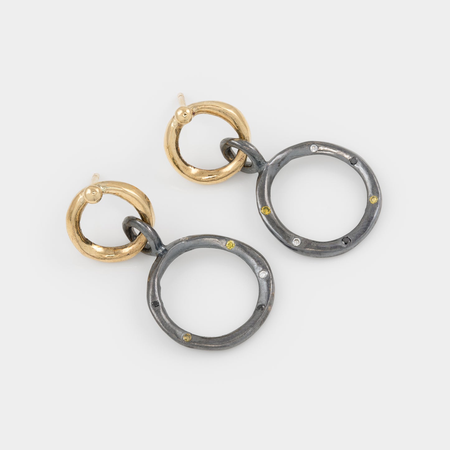 Pair of earrings with gold and silver rings on a light gray background