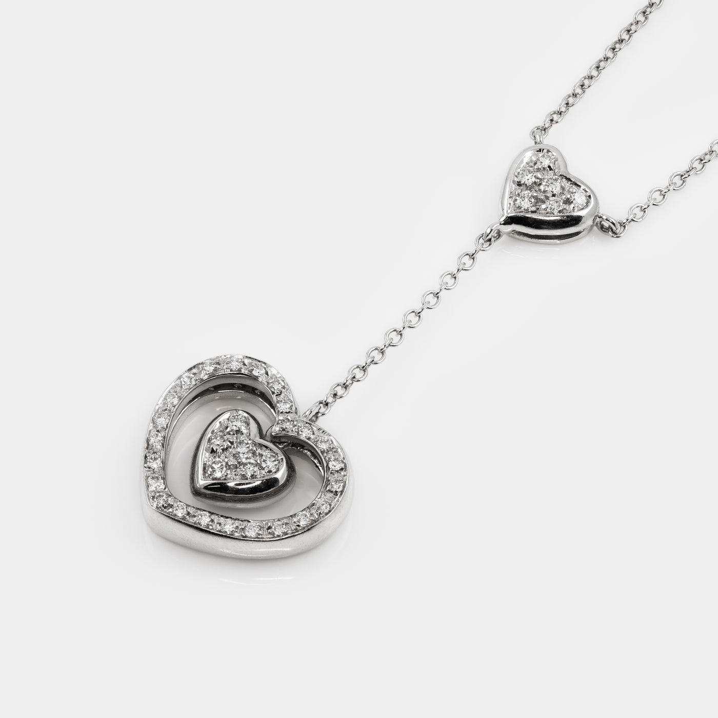 Heart-shaped silver necklace with embedded diamonds on a white background