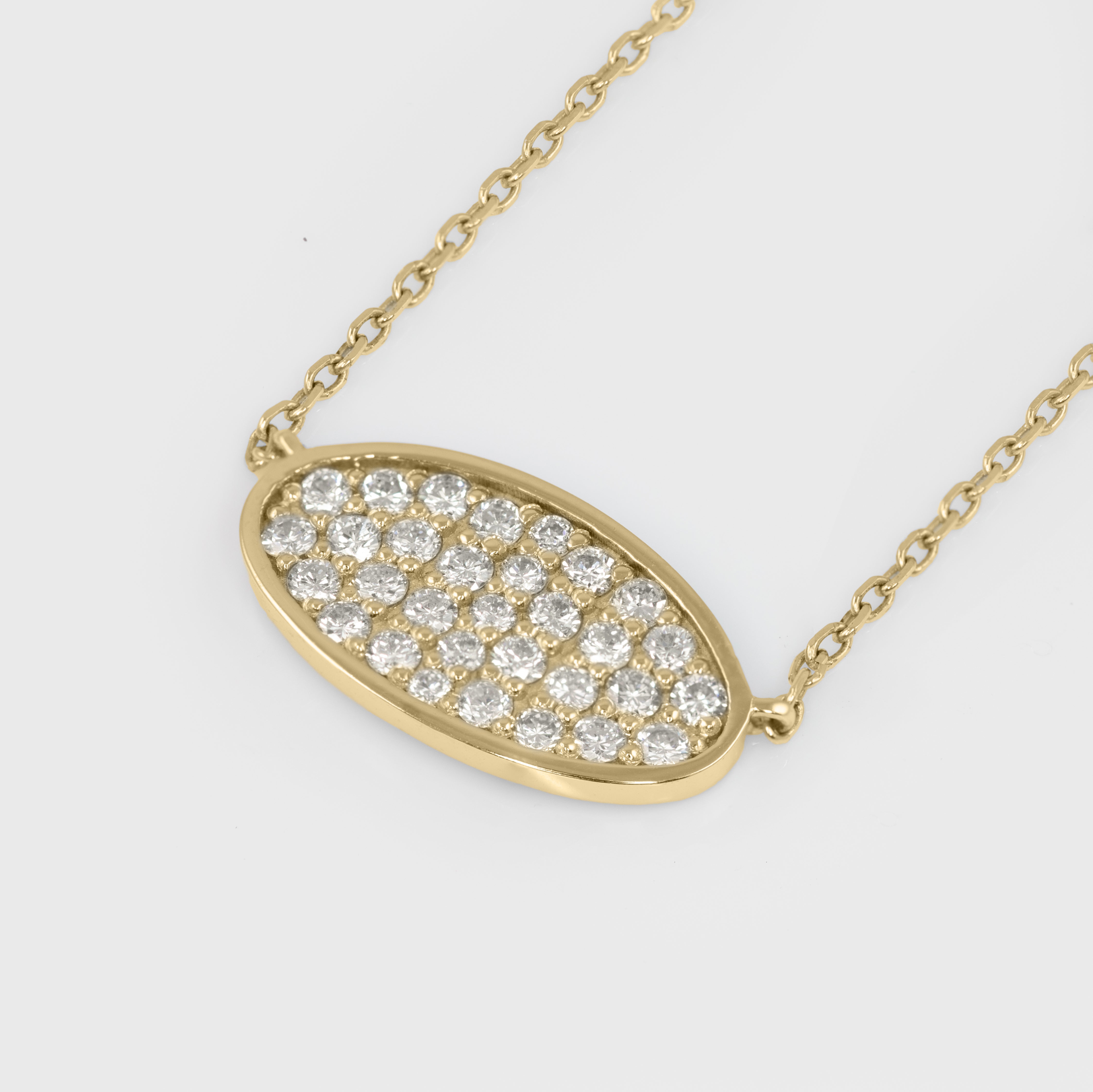 Gold necklace with a diamond-encrusted pendant on a light gray background