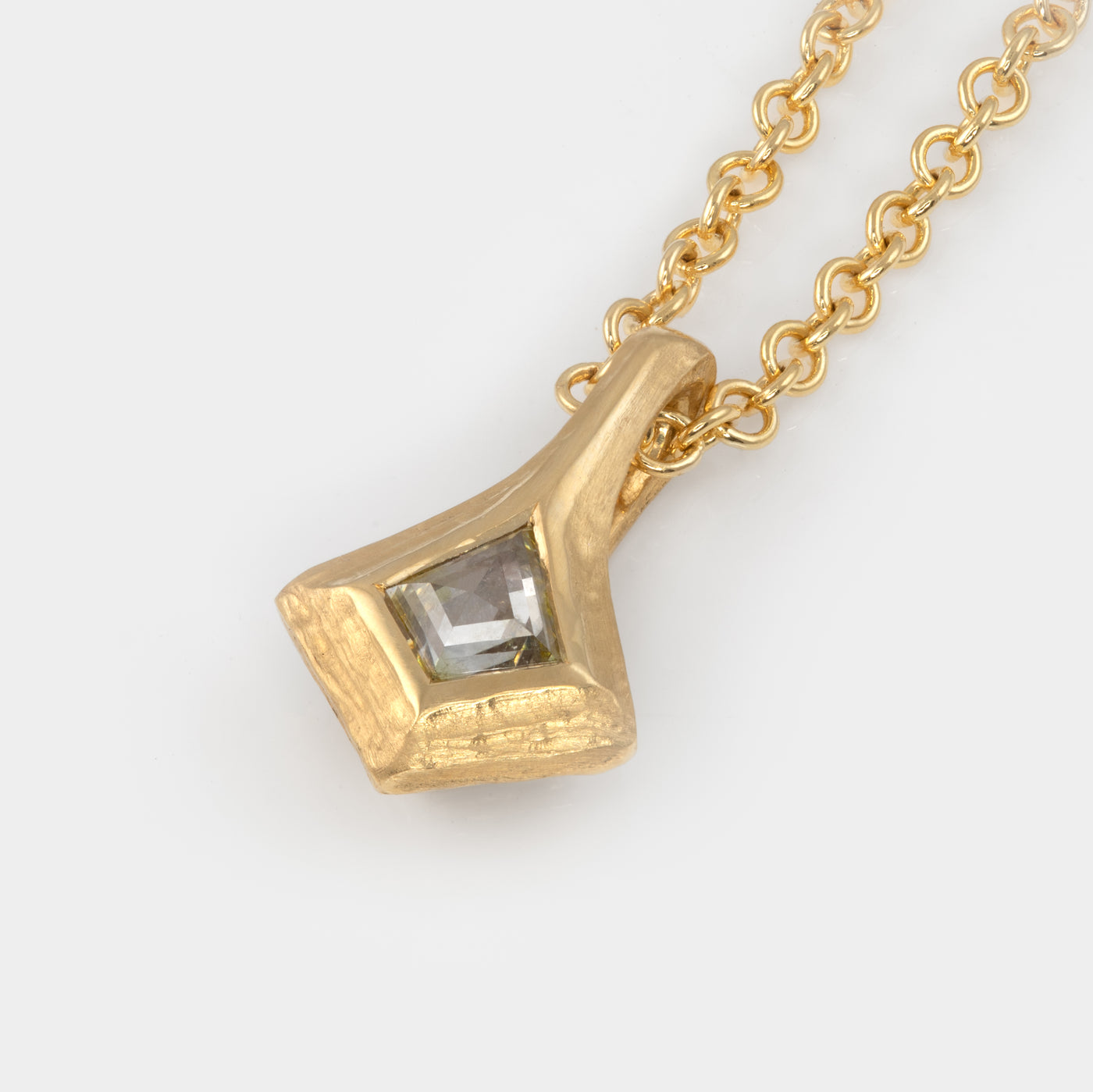 Light yellow kite-shaped diamond in gold kite pendant, on white background
