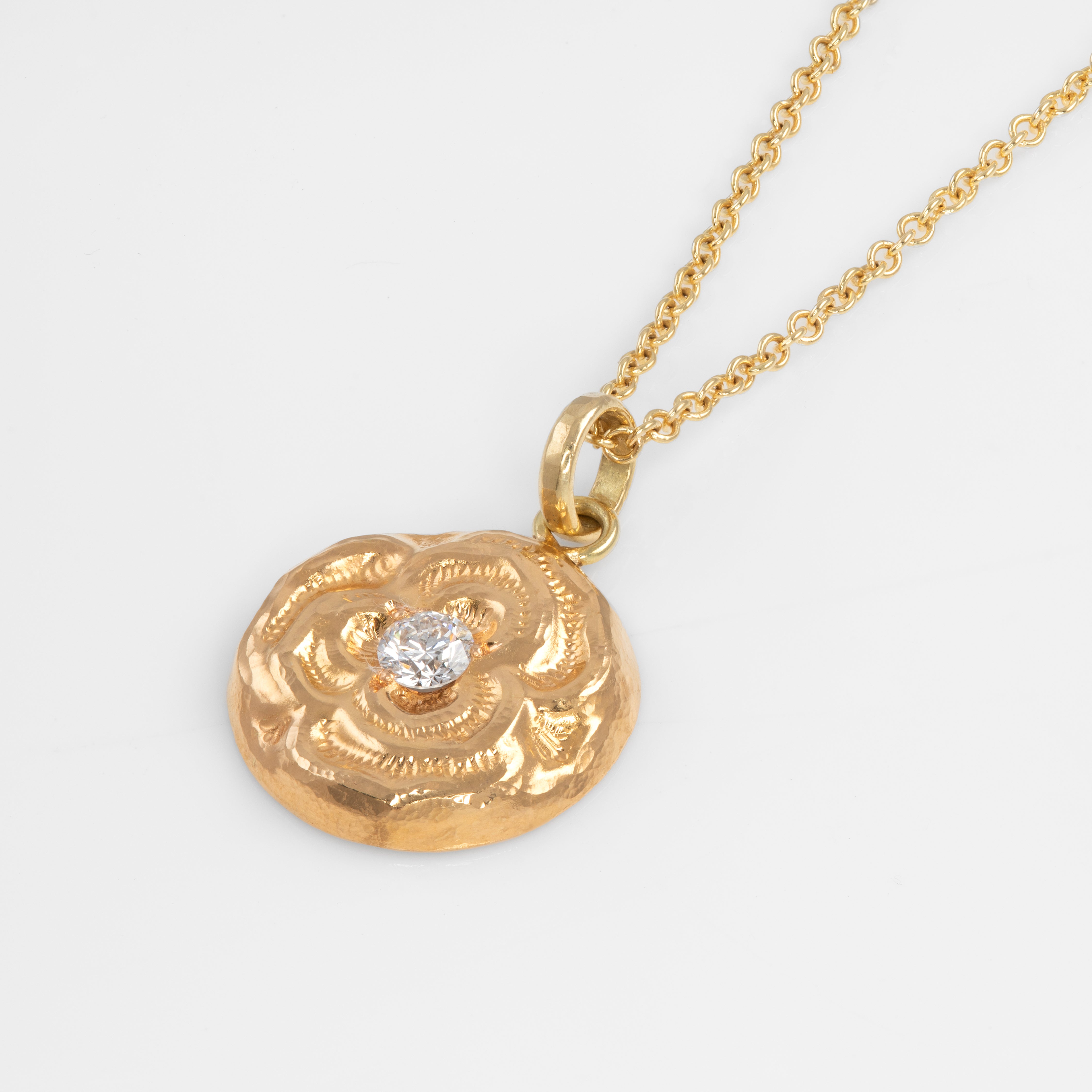 Gold necklace with a decorative pendant on a white background