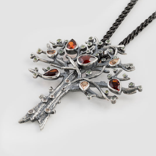 Silver tree-shaped pendant with gemstones on a white background