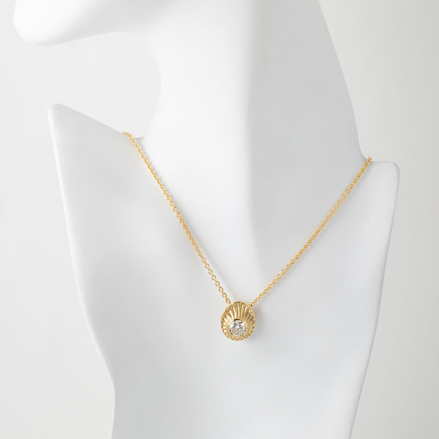 Gold necklace with a pendant on a mannequin bust against a white background