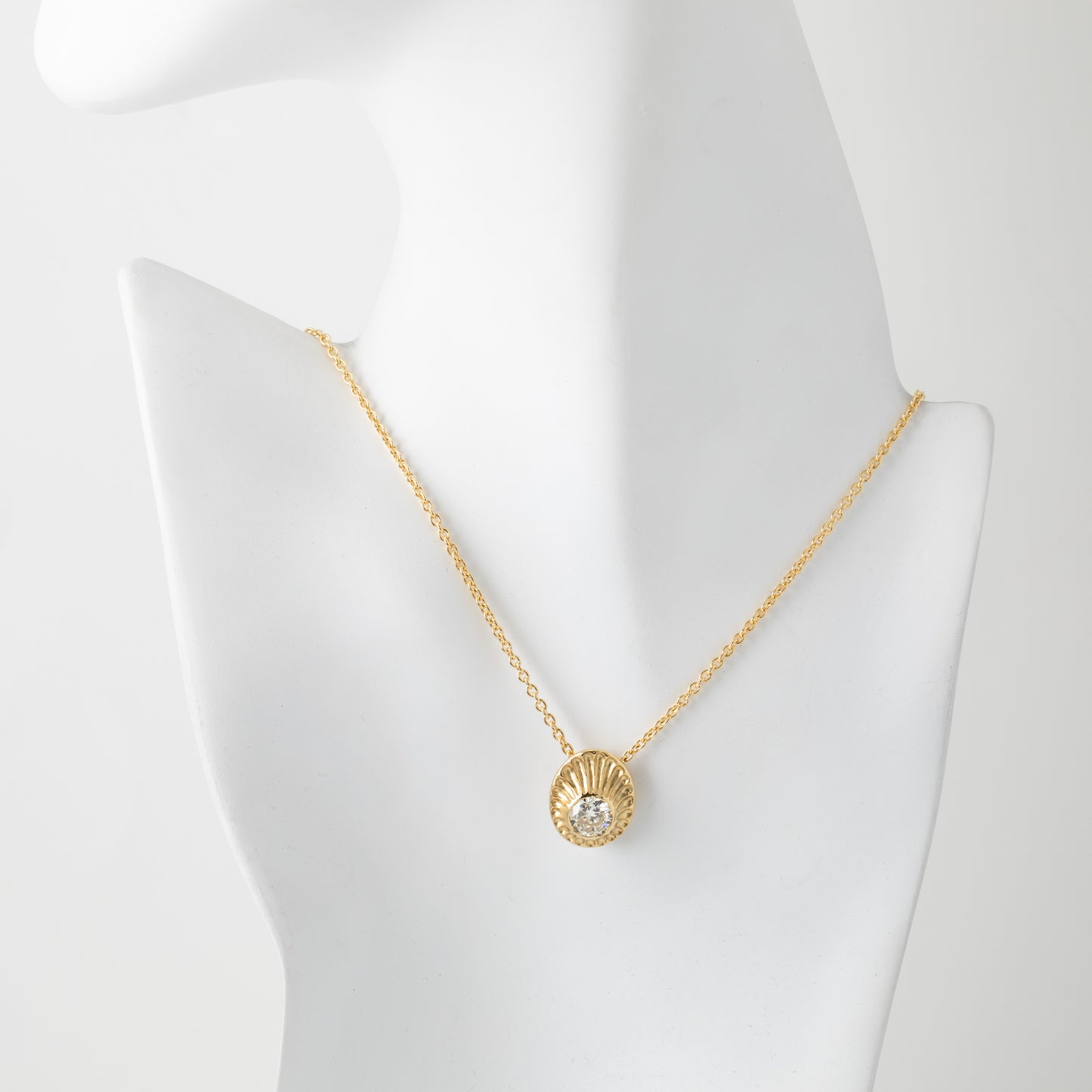 Gold necklace with a pendant on a mannequin bust against a white background