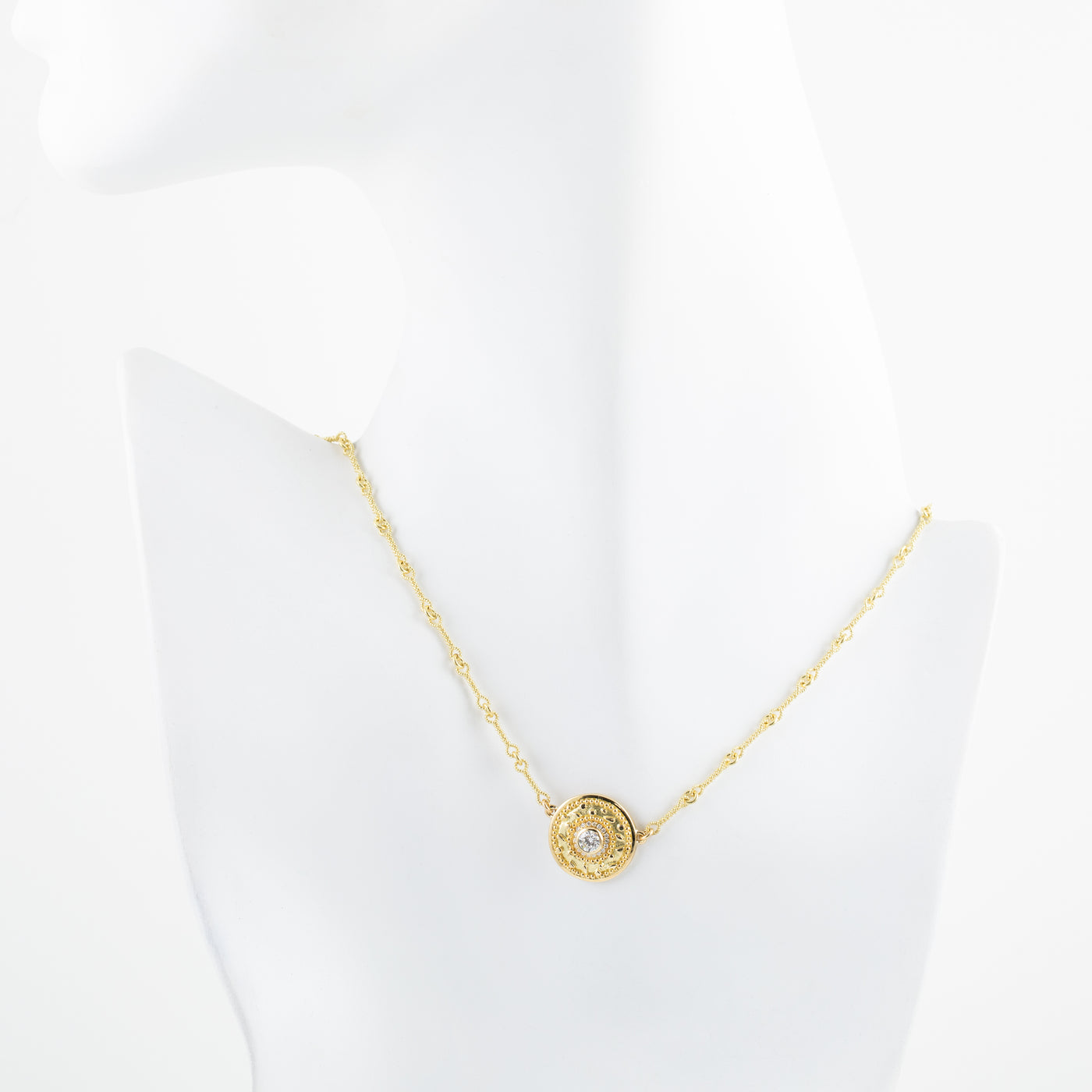 Gold necklace with a circular pendant on a white mannequin