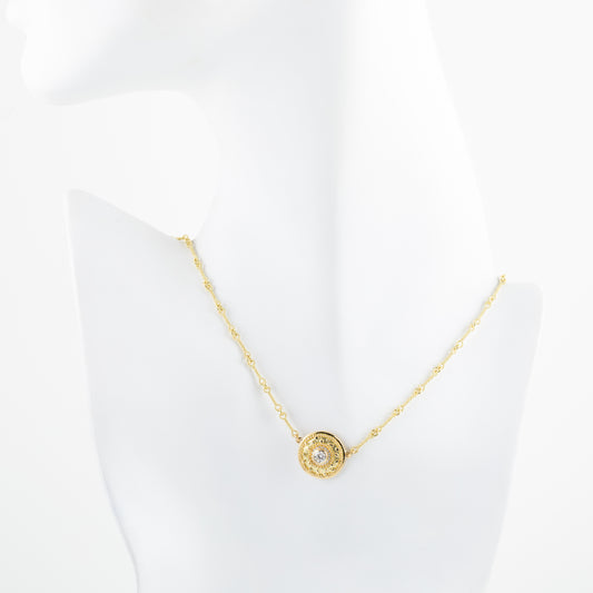 Gold necklace with a circular pendant on a white mannequin