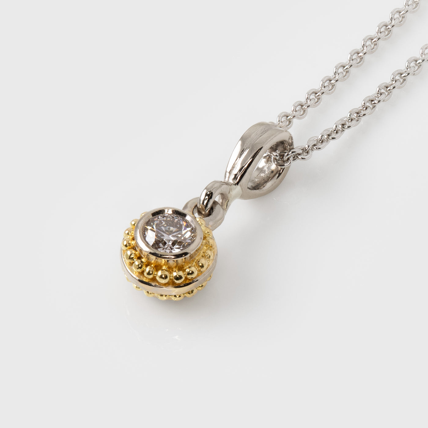 Two-tone diamond pendant on a chain against a white background