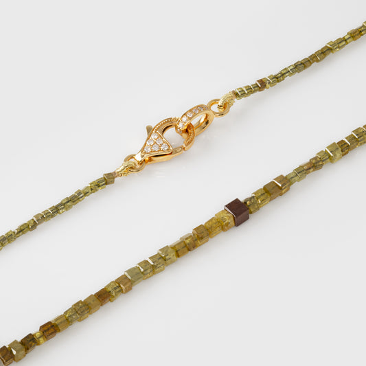 Gold and green beaded necklace on a white background