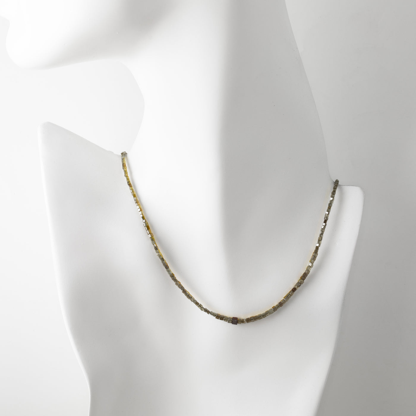 Green beaded necklace on a mannequin with a plain background