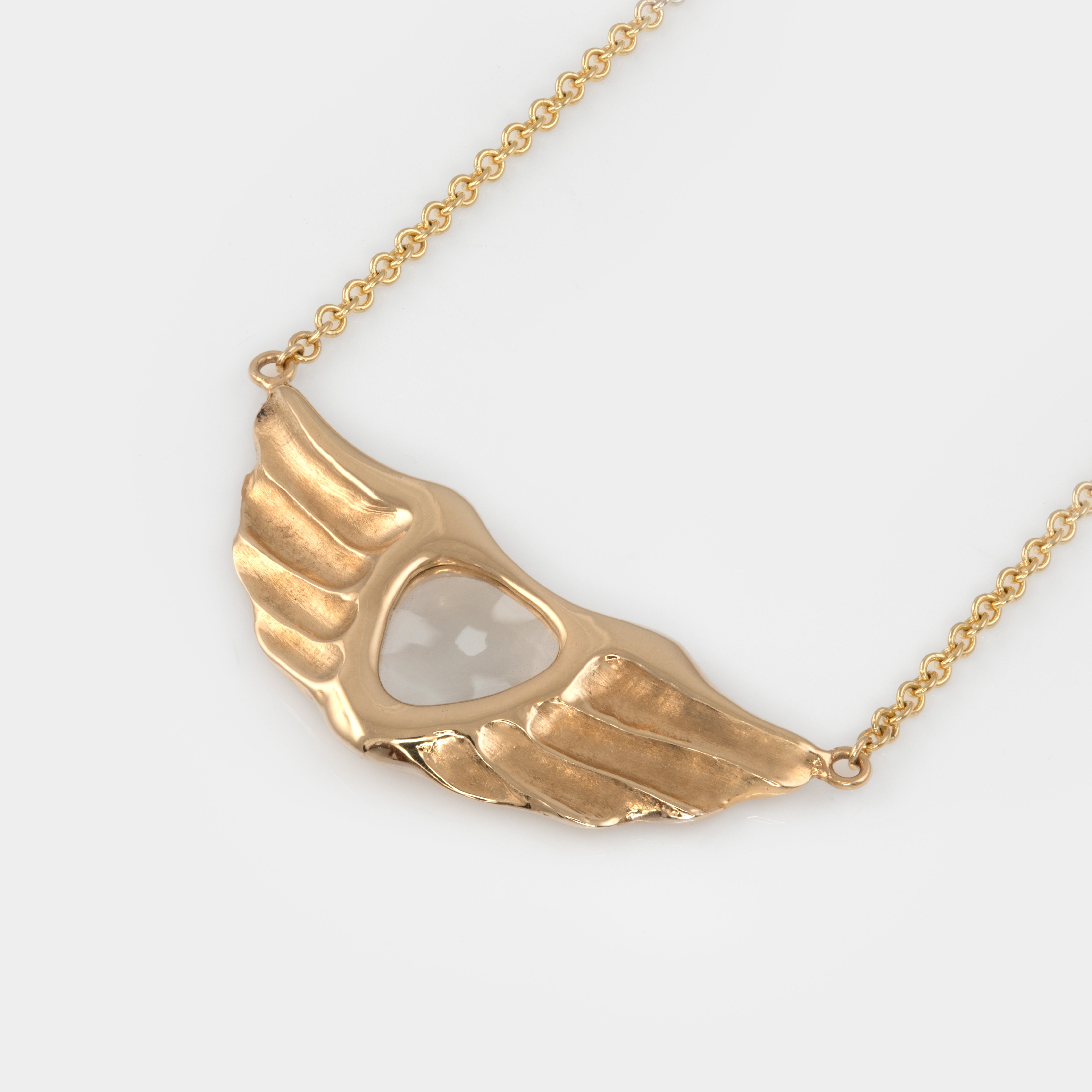 Gold wing-shaped necklace on a white background