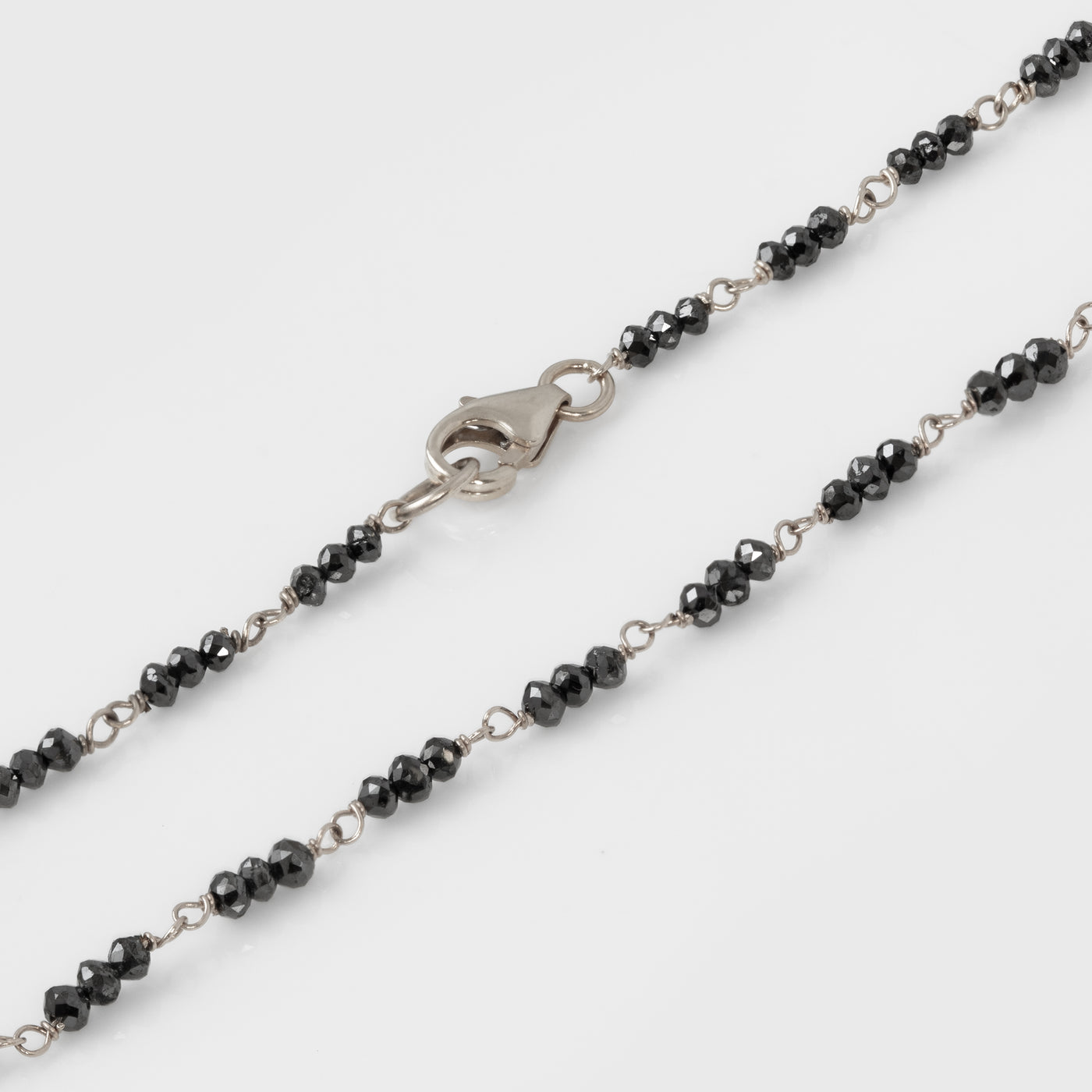 Bracelet with black beads and white gold clasp on a white background